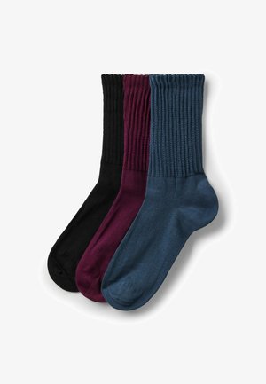Tre paia di calzini a coste, color neri, borgogna e blu navy, ordinatamente impilati su uno sfondo bianco.