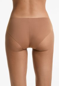 Naadloze bruine slip met een gladde textuur, een middelhoge snit en minimale bedekking aan de achterkant, die een eenvoudig, functioneel ontwerp toont.