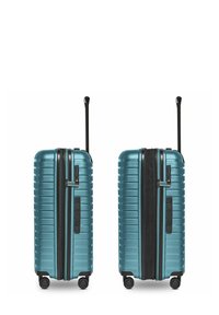 Maleta rígida de color teal, con ranuras verticales, cremallera negra, asa retráctil y cuatro ruedas giratorias para mayor movilidad.