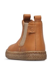 Stivale alla caviglia in pelle tan con pannelli laterali elastici, linguette per la presa e suola in gomma testurizzata. Presenta una punta arrotondata e dettagli di cucitura semplici.