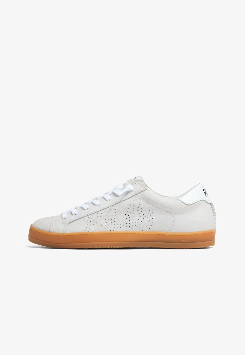 Basket basse en daim blanc avec motif latéral perforé, lacets blancs, languette de talon blanche et semelle en caoutchouc marron clair.