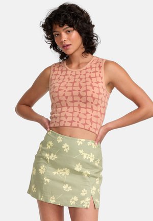 Top corto de crochet en rosa con un patrón floral, combinado con una mini falda verde claro que presenta estampados de flores amarillas y una abertura lateral.