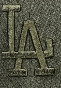 Dunkelgrüner Cap aus strukturiertem Stoff, mit eingesticktem "LA"-Logo in passendem grünen Faden. Markantes Muster verbessert die Sichtbarkeit der Details.