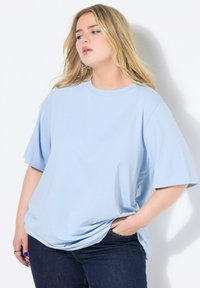 Světle modré tričko s krátkým rukávem z měkké bavlny, s kulatým výstřihem a volným střihem. V kombinaci s tmavými džíny.