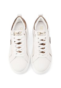 Sneakers in pelle bianca con accenti marroni sul tallone, spesse stringhe bianche e un logo dorato discreto sulla linguetta e sul lato. Design con punta rotonda.