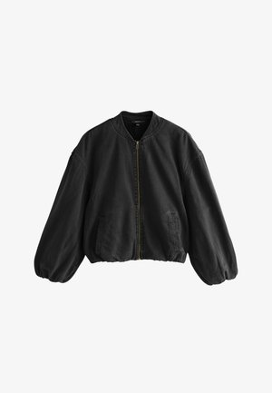 Čierna nadmerná bomber bunda so zipsom na prednej strane, dvoma bočnými vreckami, elastickými manžetami a lemom, vyrobená z mäkkého materiálu.