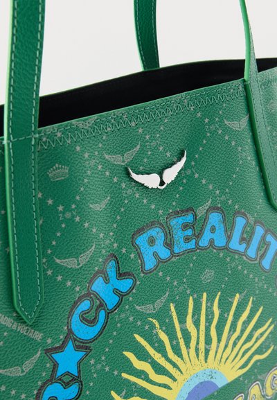 Πράσινη υφασμάτινη τσάντα tote με μπλε και κίτρινο γραφικό ήλιου, κείμενο «Rock Reality», μικρό έμβλημα φτερού και σχέδια φτερών εκτυπωμένα στην επιφάνεια.