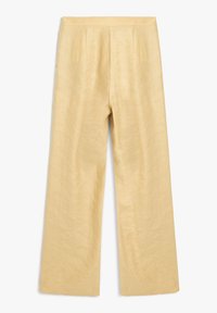 Pantaloni a gamba larga di un giallo chiaro realizzati in un tessuto strutturato con una finitura liscia. Presentano pieghe cucite con cura e una silhouette rilassata.
