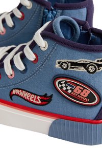 Modré plátěné tenisky s bílými šňůrkami, červenými a modrými průvleky a červenými akcenty. Obsahují vyšívané nášivky a gumovou podrážku.