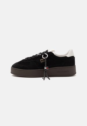 Czarny sneaker na niskiej podeszwie z białym obcasem, grubą brązową podeszwą, czarnymi sznurowadłami z metką i logo Tommy Jeans po boku podeszwy.