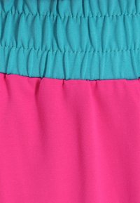 Tweekleurige elastische taille stof: bovenste gedeelte in turquoise, onderste in roze. Glad oppervlak met geplooide details bij de taille.