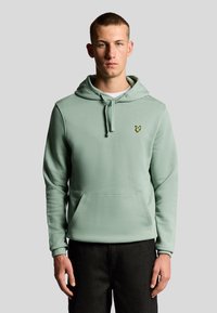 Felpa verde menta realizzata in tessuto morbido. Presenta una tasca frontale, cappuccio con cordino e un piccolo logo giallo sul lato sinistro del petto.