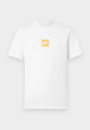 T-shirt blanc à manches courtes en coton avec un petit carré orange sur la poitrine affichant le logo Nike blanc et le swoosh.