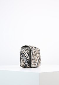 Borsa in perline con motivo a zigzag caratterizzato da accenti neri, bianchi e metallici; forma strutturata e superficie liscia.