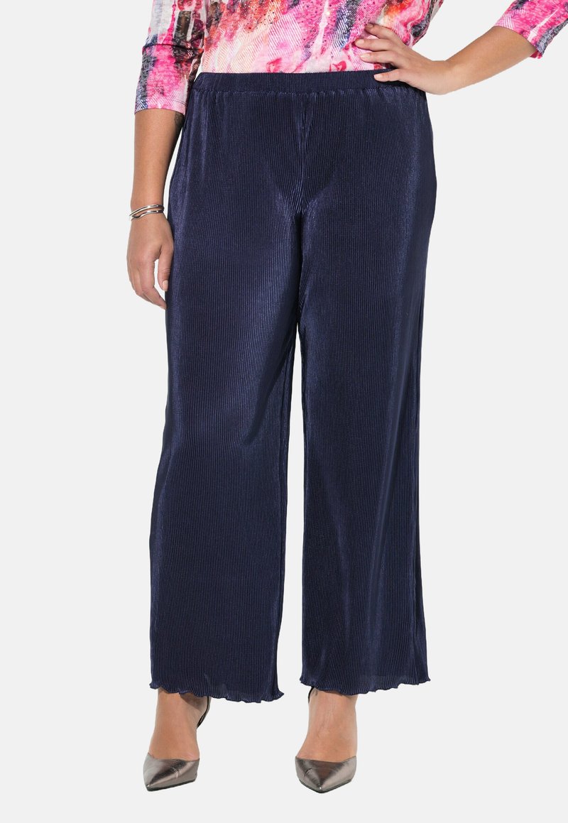 Navy corduroy levele-gait suunnikkaat, elastisella vyötäröllä ja aallotetulla helmalla, yhdistettynä hopeisiin korkokenkiin. Teksturoitu pinta on näkyvissä.