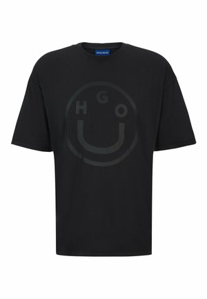 Sort bomulds T-shirt med et rundt logo, der har teksten "HGO" og et smilende ansigt designet i en lidt mørkere sort. Regular fit.