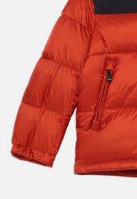 Rød isolert jakke med en puffy design, som har en svart øvre del, glidelåslomme og en glatt, blank stofftekstur.
