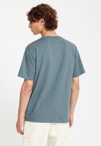 T-shirt gris à manches courtes avec col rond, fabriqué en tissu doux, offrant une coupe décontractée et sans motifs ni graphismes visibles.