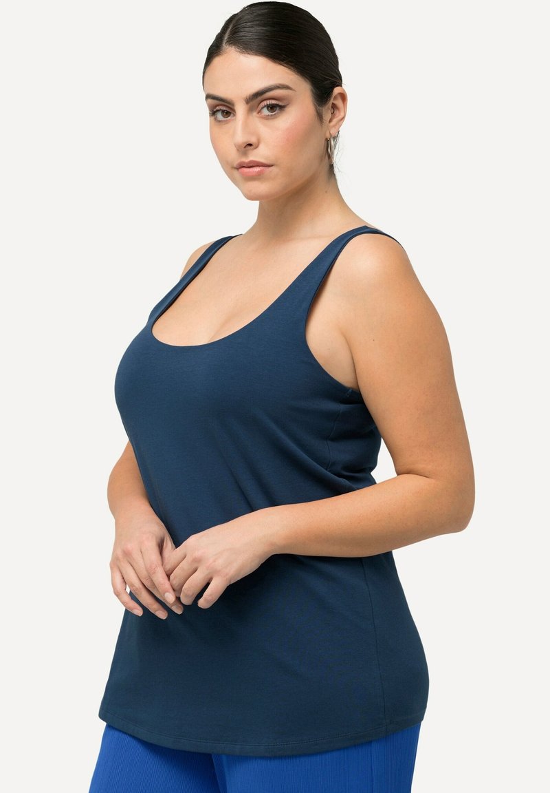 Námořnická tank top s širokými ramínky, kulatým výstřihem a zakřiveným lemem. Vyrobeno z měkké bavlněné směsi, hladká textura, uvolněný střih.