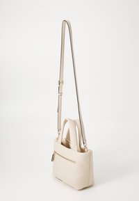 Sac à main rectangulaire beige avec des poignées doubles rembourrées, une bandoulière longue réglable et une poche zippée à l'arrière.