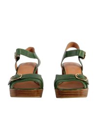 Las sandalias de cuero verde cuentan con un diseño de punta abierta, correas ajustables en el tobillo, acentos en tono dorado y un tacón de plataforma de madera.