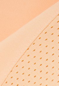 Gros plan sur un tissu de couleur pêche avec une bande texturée et un motif en maille perforée.