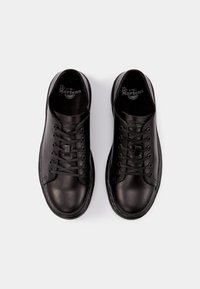 Baskets en cuir noir avec un bout rond, des lacets plats et une texture lisse. Les semelles intérieures sont marquées "Dr. Martens."