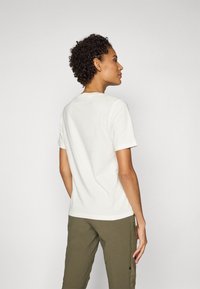 Hvid kortærmet t-shirt lavet af blødt stof, med en klassisk rund nøgleudskæring og standard pasform, båret med olivengrønne cargo bukser.