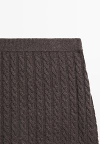 Tissu tricoté gris foncé avec une taille côtelée et un motif de tricot torsadé vertical.