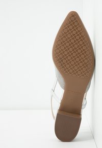 Semelle d'une chaussure à bout pointu avec une bande de roulement en caoutchouc texturé, étiquetée "Peter Kaiser" et taille 4½, avec un petit talon bloc et des brides transparentes.