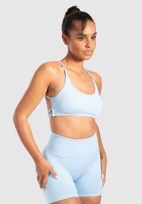 Lichtblauwe naadloze sportbeha met dunne bandjes en sluitdetails, gecombineerd met bijpassende high-waisted fietsshorts van een zacht, rekbaar materiaal.