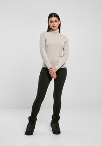 Lichtbeige lange mouwen turtleneck top gecombineerd met donkere slim-fit jeans en zwarte slouchy enkellaarsjes, met een zachte textuur.