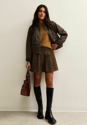 Brown bomber jacket, mustard sweater, plaid skirt, knee-high black boots, and a brown handbag. Smooth textures with noticeable patterns.
