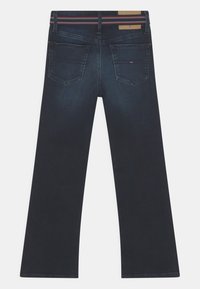 Jeans de mezclilla azul oscuro con un diseño de pierna recta, dos bolsillos traseros y un parche de cuero marrón con detalles en rojo y blanco en la cinturilla.