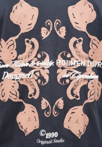 Ανισομερές ροζ λουλουδάτο μοτίβο σε σκούρο ύφασμα με λευκό κείμενο που περιλαμβάνει "HOLMEN DISTR" και "© 1990 Originals Studio" σε στρωματοποιημένες γραμματοσειρές.