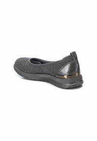 Zapato negro de punto sin cordones con un upper texturizado, puntera redondeada y un elegante acento de tacón negro brillante. Suela de goma flexible con un leve relieve.