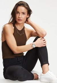 Brun ribbet halterneck top, lagede sølv halskæder, sorte skinny jeans, sølv ur med meshrem, og hvide sneakers.