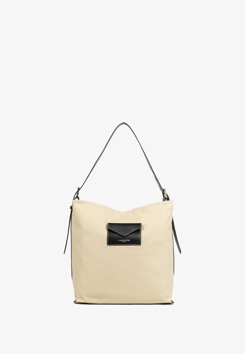 Beige canvas schoudertas met een zwarte leren accentzak en schouderriem. Kenmerkt zich door een strak ontwerp met een ronde bovenkant en een ritssluiting.