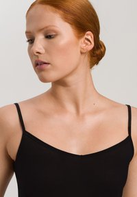 Svart camisole med tunna axelband, med V-ringning och slät textur, framför en neutral bakgrund.