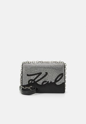 Borsa nera e argento impreziosita da strass con tracolla a catena, caratterizzata dalla scritta “Karl” in materiale nero testurizzato sul davanti.