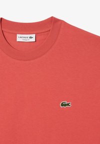 T-shirt in cotone corallo con vestibilità classica, collo a coste e piccolo logo di coccodrillo ricamato in verde sul petto.