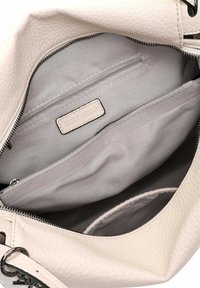 Intérieur de sac à main beige clair texturé avec une doublure grise lisse, comportant une poche zippée et un compartiment principal pour l'organisation.