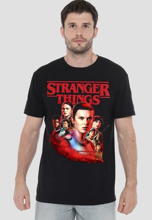 Black cotton t-shirt featuring a colorful graphic of characters from "Stranger Things" with red text and a swirling red background.