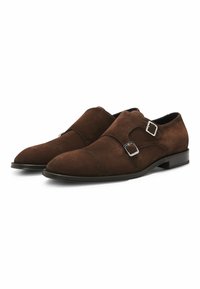 Brown suede double monk strap shoes with silver buckle accents, sleek rounded toe, and a flat rubber sole. Soft texture, modern design.