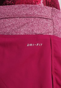Pantalones cortos deportivos de color granate con una cintura texturizada, con la marca "DRI-FIT" en blanco. Tela lisa y diseño ajustado.