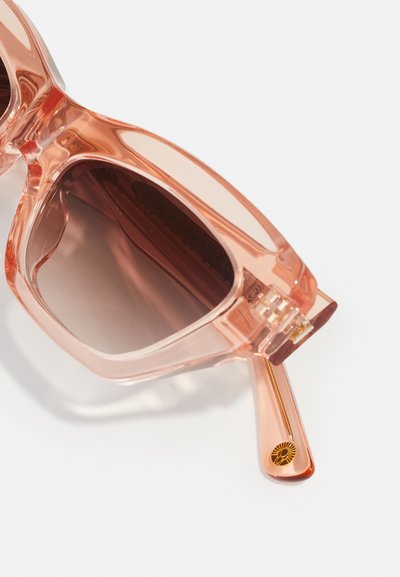 Rosa genomskinliga solglasögon med fyrkantiga bågar, gradientbruna linser och guldaccenterade skalmar med en solstråledesign.