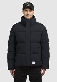 Must have rõngas must puffer-jope, millel on kõrge krae, horisontaalne polsterdus ja esi-taskud. Sisaldab logo pazhi allääres.