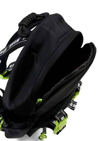Zaino nero con accenti verdi, zip parzialmente aperta, tracolle marchiate in bianco e nero e manico in corda nera arricciata su sfondo bianco.