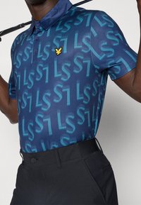 Koszulka polo z krótkim rękawem w ciemnoniebieskim kolorze z powtarzającym się jasnoniebieskim wzorem "LS", z żółtym logo orła na piersi i kołnierzykiem.