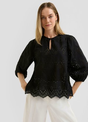 Zwart geborduurd blouse met een ronde hals en sleutelgatdetail. Heeft pofmouwen en een scalloped zoom met uitsnijdingen.